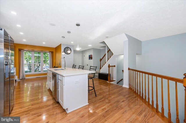 kitchen featuring light wood-style flooring, a sink, a breakfast bar, stainless steel appliances, and light countertops