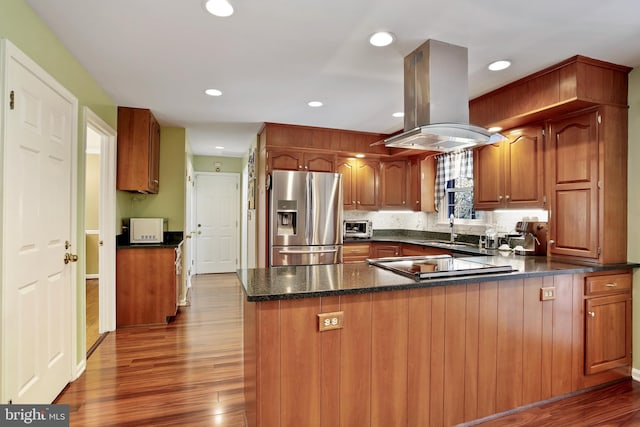 kitchen with a sink, dark wood-style flooring, stainless steel fridge, island exhaust hood, and white microwave