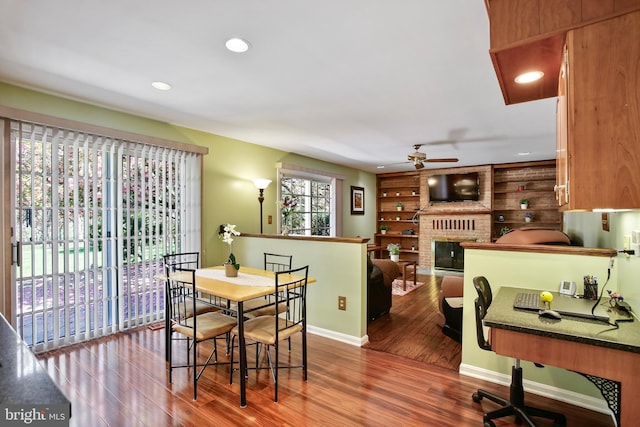 dining space with recessed lighting, a brick fireplace, ceiling fan, baseboards, and wood finished floors