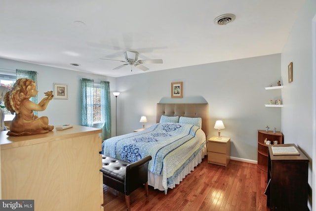 bedroom with a ceiling fan, hardwood / wood-style floors, baseboards, and visible vents