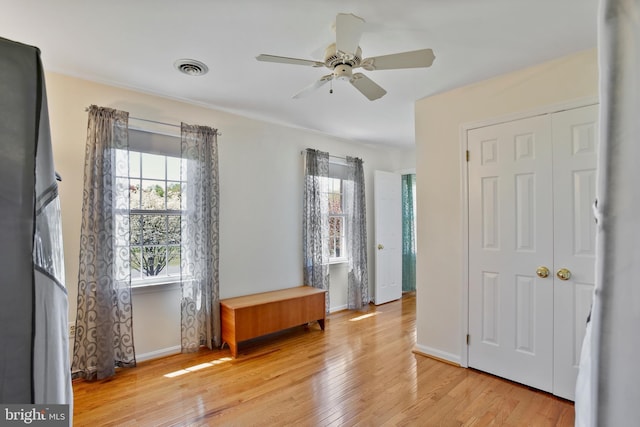 unfurnished bedroom featuring light wood-style floors, a closet, ceiling fan, visible vents, and baseboards