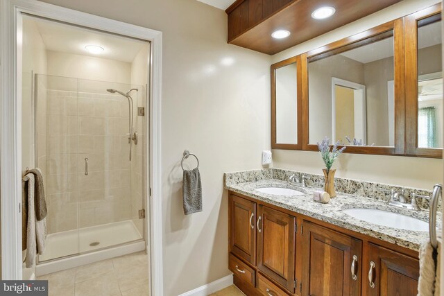 bathroom featuring a stall shower, double vanity, a sink, and tile patterned floors