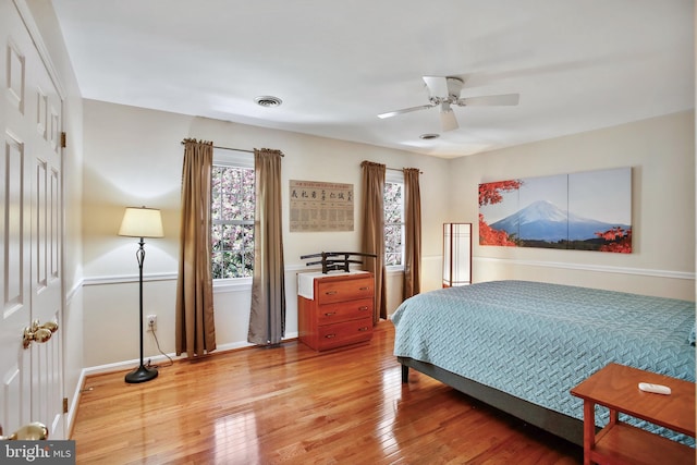 bedroom with baseboards, visible vents, a ceiling fan, and light wood-style flooring