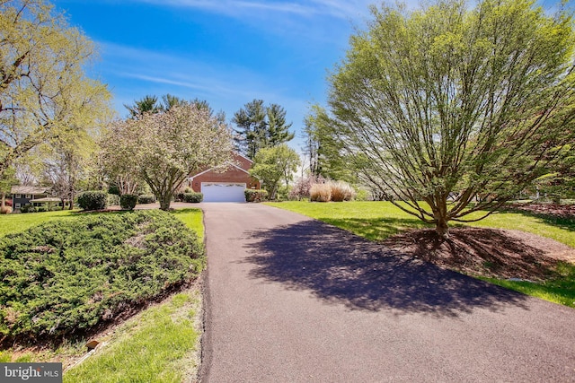 view of front of property with a front yard, a garage, and aphalt driveway