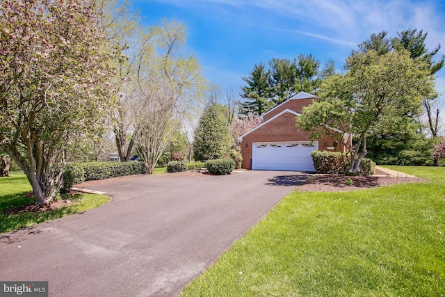 view of side of property featuring a lawn, aphalt driveway, brick siding, and a garage