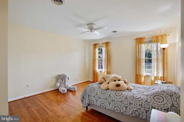 bedroom featuring wood finished floors, ceiling fan, visible vents, and baseboards