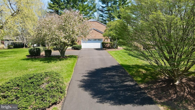 view of front facade featuring an attached garage, aphalt driveway, and a front lawn