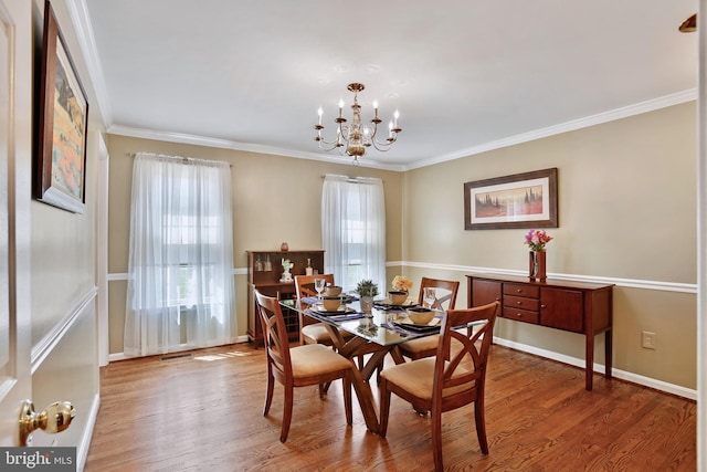 dining space with visible vents, ornamental molding, an inviting chandelier, and wood finished floors