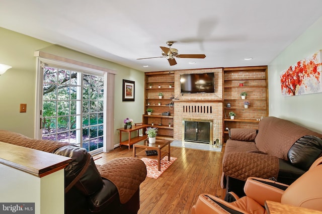 living room featuring recessed lighting, wood finished floors, ceiling fan, built in shelves, and a fireplace