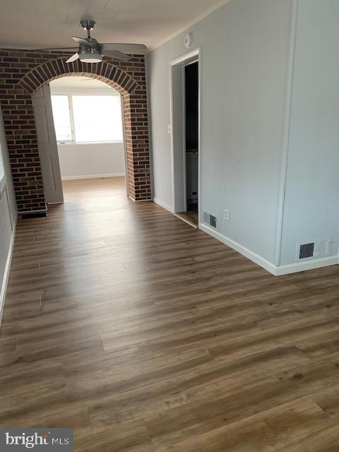 515 Wood St, Baltimore, MD 21225 - unfurnished room featuring a ceiling fan, wood finished floors, baseboards, arched walkways, and crown molding