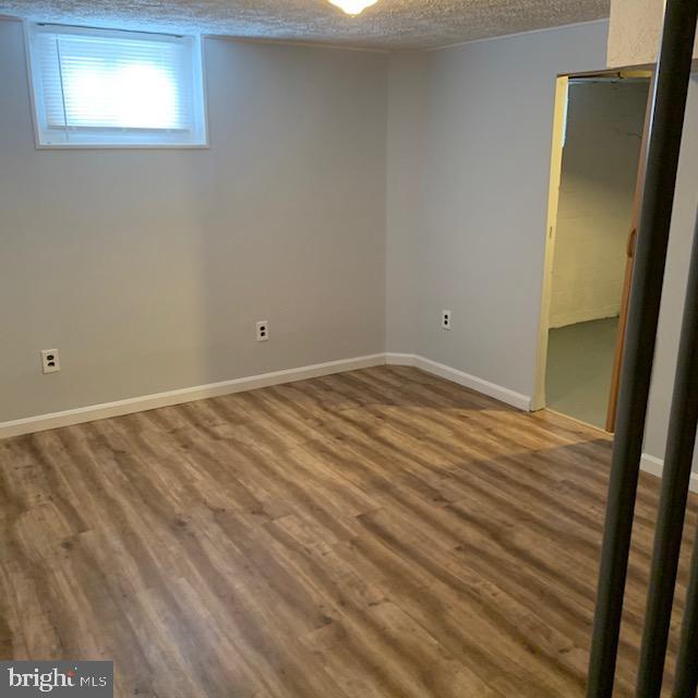 515 Wood St, Baltimore, MD 21225 - basement featuring wood finished floors, a textured ceiling, and baseboards
