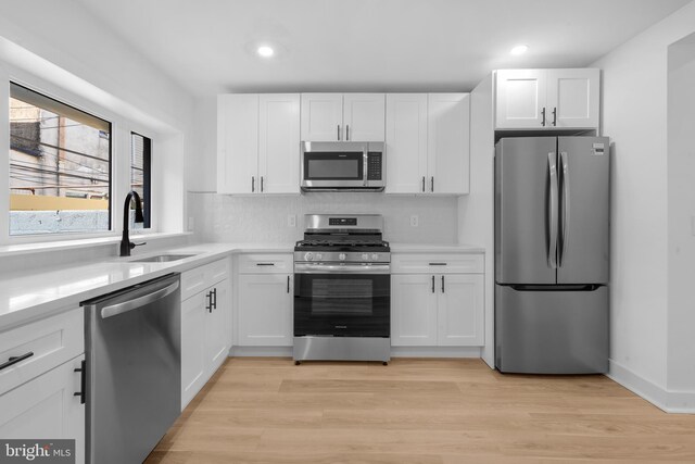 kitchen featuring recessed lighting, stainless steel appliances, light countertops, a sink, and white cabinetry