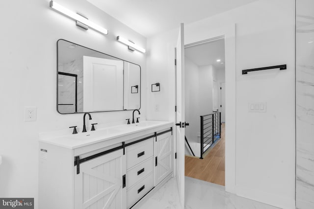 full bathroom featuring double vanity, marble finish floor, and a sink