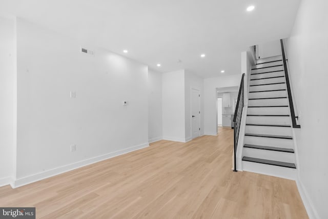 unfurnished living room featuring visible vents, baseboards, light wood-style floors, recessed lighting, and stairs