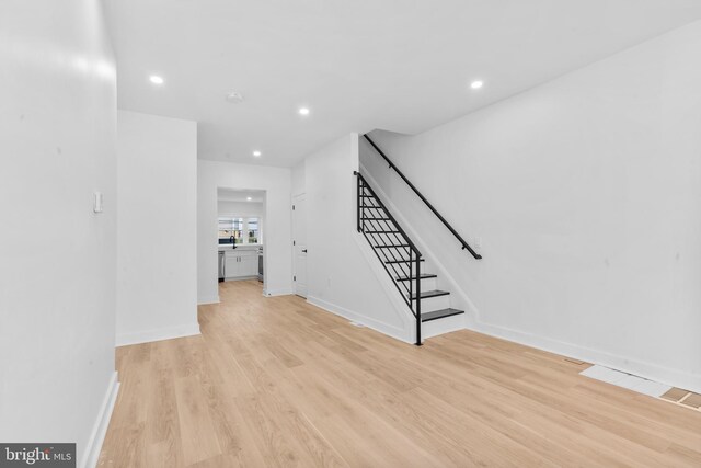 unfurnished living room featuring light wood-style flooring, visible vents, baseboards, recessed lighting, and stairway