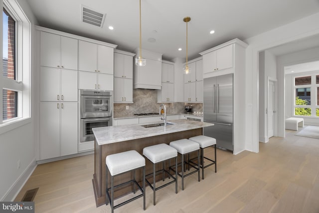 227 S Union St, Alexandria, VA 22314 - kitchen with visible vents, light wood-type flooring, tasteful backsplash, a sink, and stainless steel appliances
