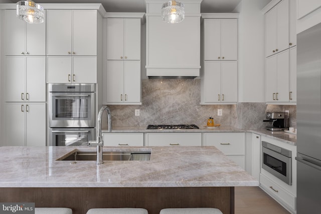 227 S Union St, Alexandria, VA 22314 - kitchen featuring pendant lighting, a kitchen breakfast bar, white cabinets, a sink, and appliances with stainless steel finishes