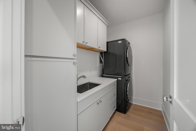 227 S Union St, Alexandria, VA 22314 - washroom with cabinet space, a sink, light wood-style flooring, baseboards, and stacked washer / dryer