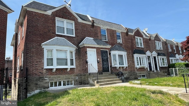 townhome / multi-family property with brick siding, fence, a residential view, and entry steps