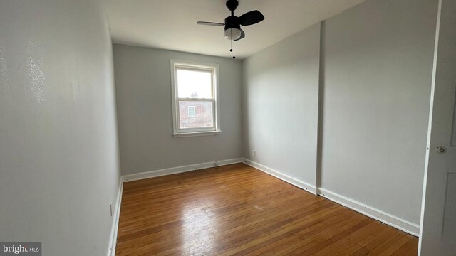 empty room featuring ceiling fan, baseboards, and wood finished floors