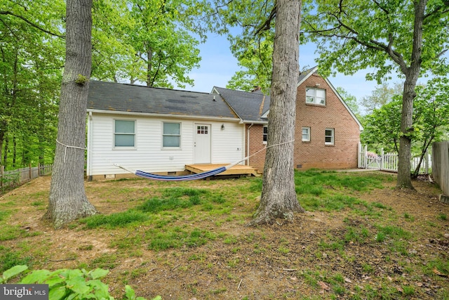 rear view of property featuring fence and crawl space
