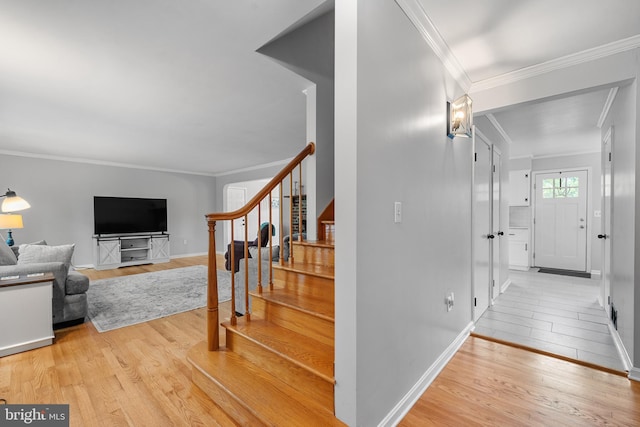 stairway featuring baseboards, ornamental molding, and wood finished floors