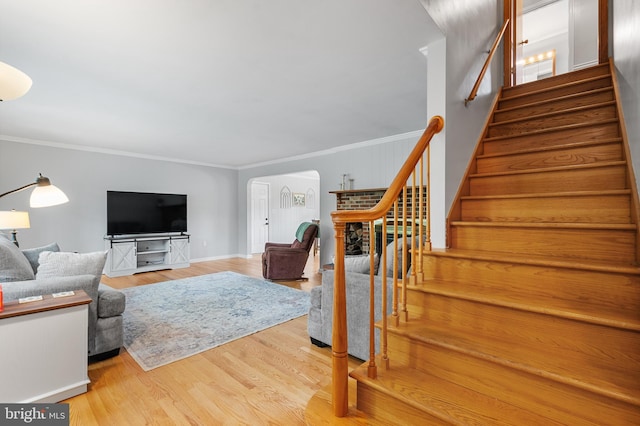 living room featuring stairs, arched walkways, crown molding, and wood finished floors