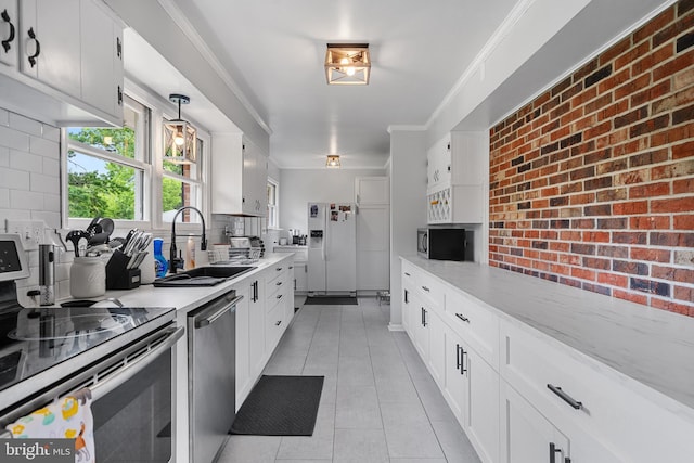kitchen with a sink, stainless steel appliances, light tile patterned flooring, and white cabinetry