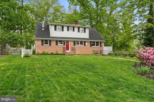 view of front facade with a chimney, roof with shingles, brick siding, fence, and a front lawn