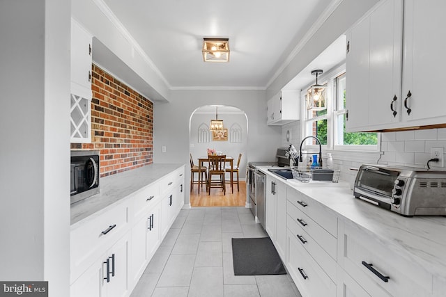 kitchen with decorative backsplash, arched walkways, a toaster, white cabinets, and stainless steel microwave