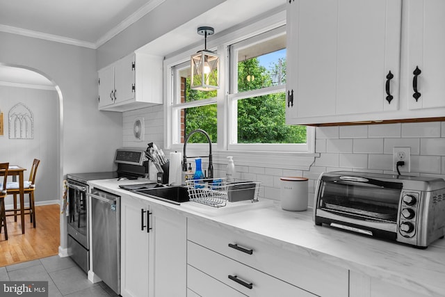 kitchen featuring appliances with stainless steel finishes, arched walkways, a sink, a toaster, and white cabinets
