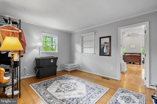interior space featuring visible vents, baseboards, crown molding, and wood finished floors