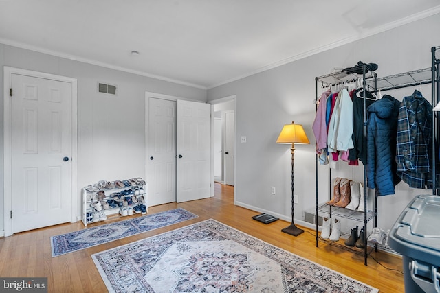 interior space featuring crown molding, baseboards, visible vents, and wood finished floors