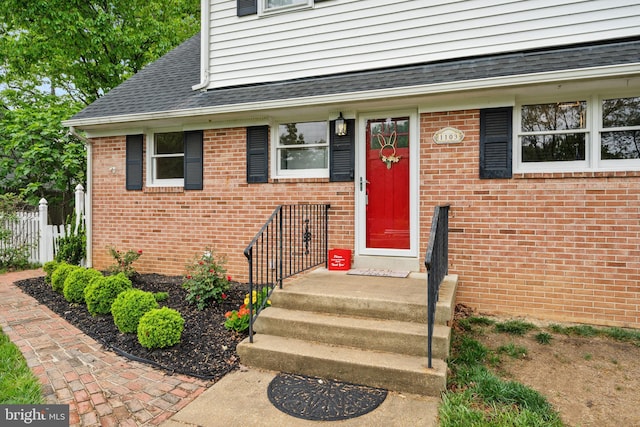 doorway to property with fence and brick siding