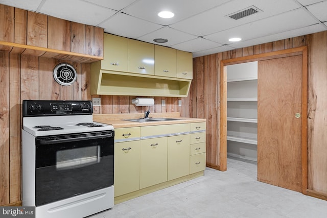 kitchen featuring wooden walls, a sink, light countertops, electric stove, and visible vents