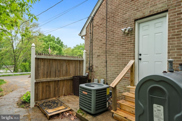 exterior space with brick siding, cooling unit, fence, and heating fuel