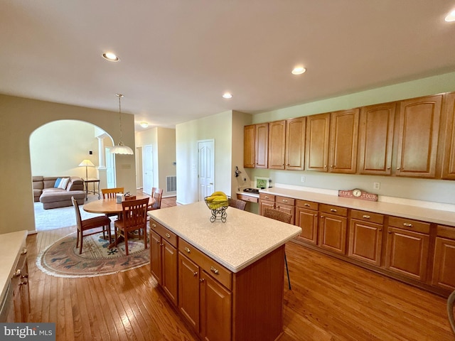 14100 Twisting Ln, Dayton, MD 21036 - kitchen featuring dark wood-type flooring, arched walkways, a kitchen island, light countertops, and brown cabinetry
