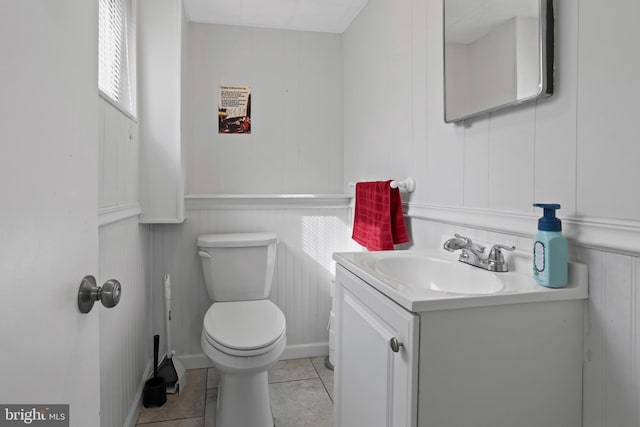 bathroom featuring a decorative wall, toilet, vanity, and tile patterned floors