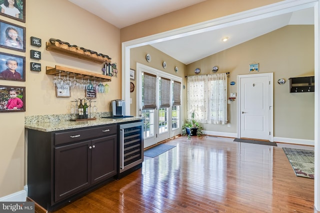 bar with wine cooler, dark wood-type flooring, baseboards, a dry bar, and lofted ceiling