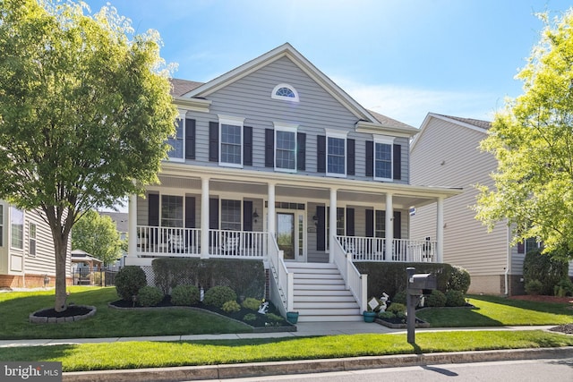 colonial-style house featuring a front lawn, stairway, and covered porch
