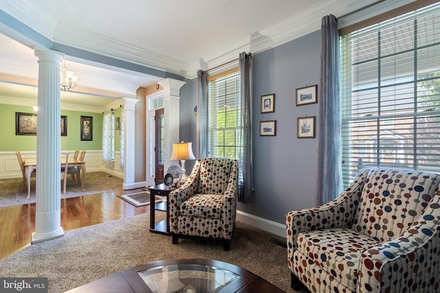 sitting room featuring ornate columns, wood finished floors, a wainscoted wall, and crown molding