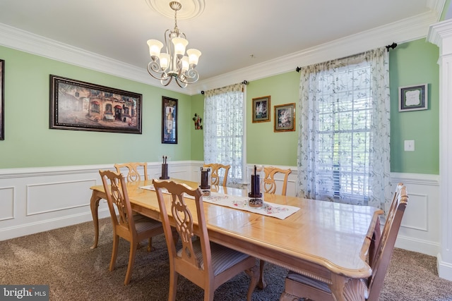carpeted dining room with a decorative wall, a chandelier, crown molding, and a wainscoted wall