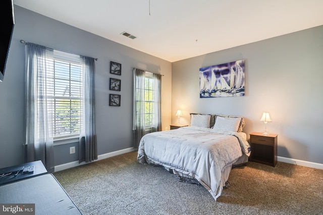 carpeted bedroom featuring visible vents, multiple windows, and baseboards