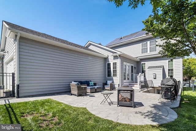 rear view of house with a lawn, french doors, an outdoor living space with a fire pit, and a patio area