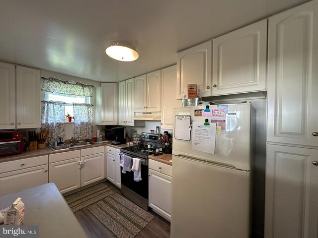 kitchen with a sink, under cabinet range hood, white cabinetry, stainless steel electric stove, and freestanding refrigerator