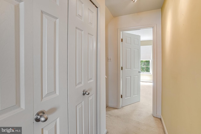 hallway featuring baseboards and light colored carpet