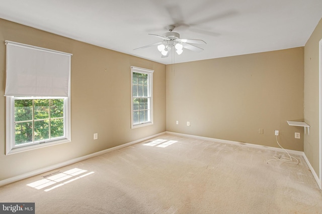 carpeted spare room featuring ceiling fan, visible vents, and baseboards