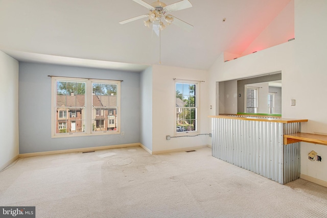 carpeted empty room with baseboards, ceiling fan, visible vents, and high vaulted ceiling