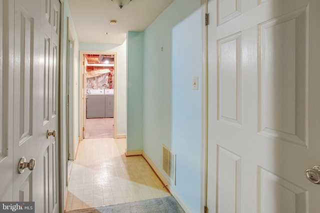 corridor featuring separate washer and dryer, baseboards, and visible vents
