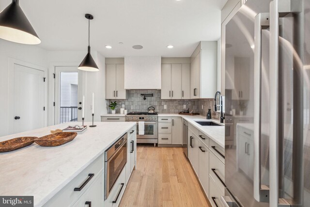 kitchen featuring recessed lighting, light wood-style flooring, decorative backsplash, appliances with stainless steel finishes, and a sink